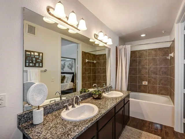 a bathroom with a granite countertop sink a mirror and a bathtub