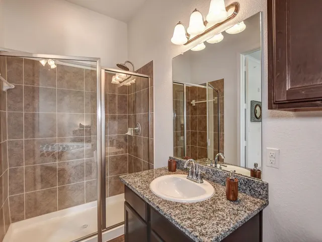a bathroom with a granite countertop sink a mirror and a shower