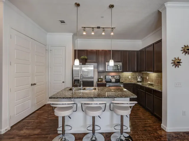 a kitchen with kitchen island granite countertop a sink and refrigerator
