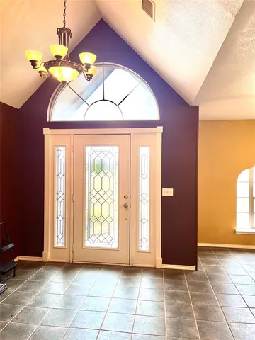 a view of empty room with window and chandelier