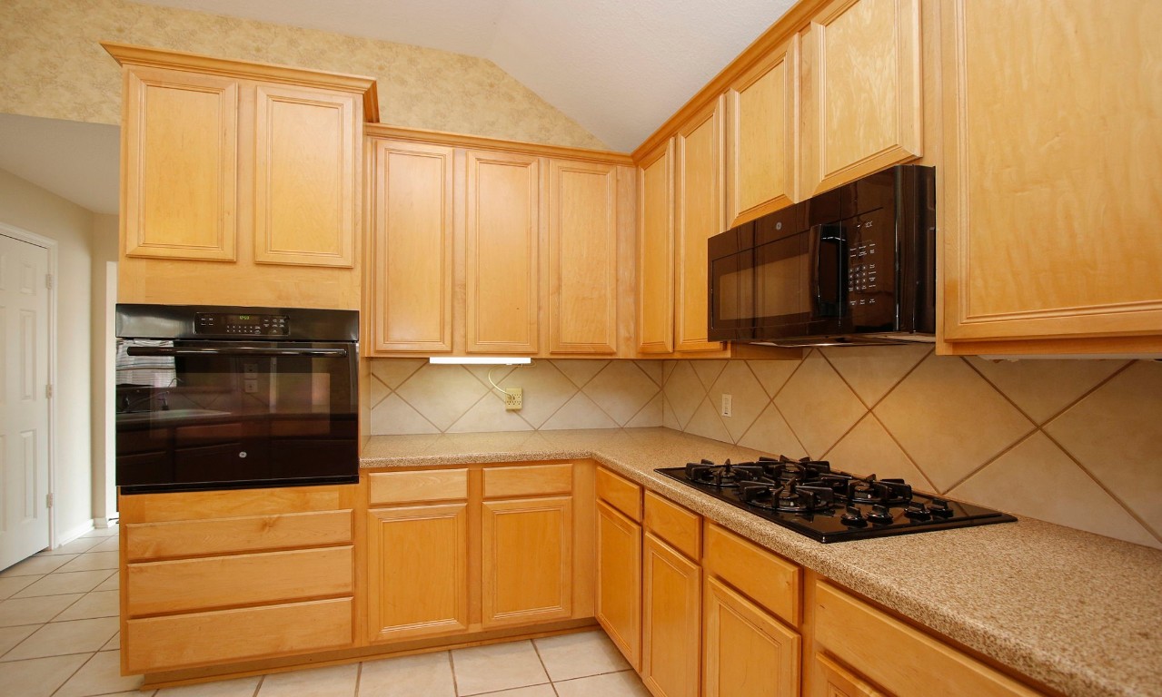 1114 Bringewood Chase Drive Spring, TX 77379 - Photo 18 of 49 a kitchen with stainless steel appliances a stove a microwave and cabinets