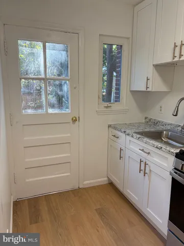a kitchen with granite countertop white cabinets and a window