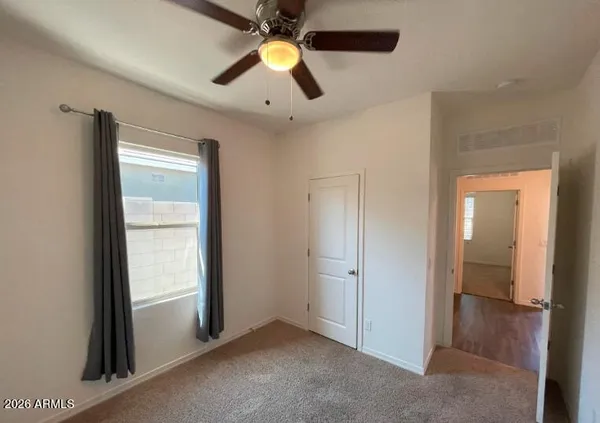 an empty room with closet and a chandelier fan