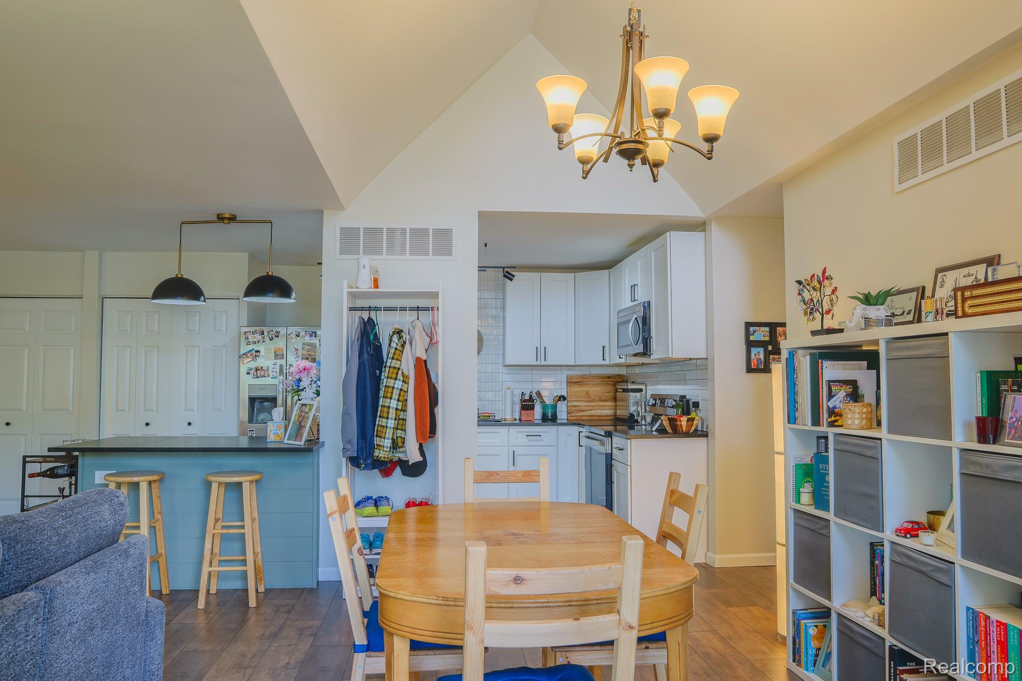 1989 Klingensmith Road, Unit 46 Bloomfield Hills, MI 48302 - Photo 12 of 41 Open-concept dining area with vaulted ceilings, wood-finish flooring, and a contemporary chandelier