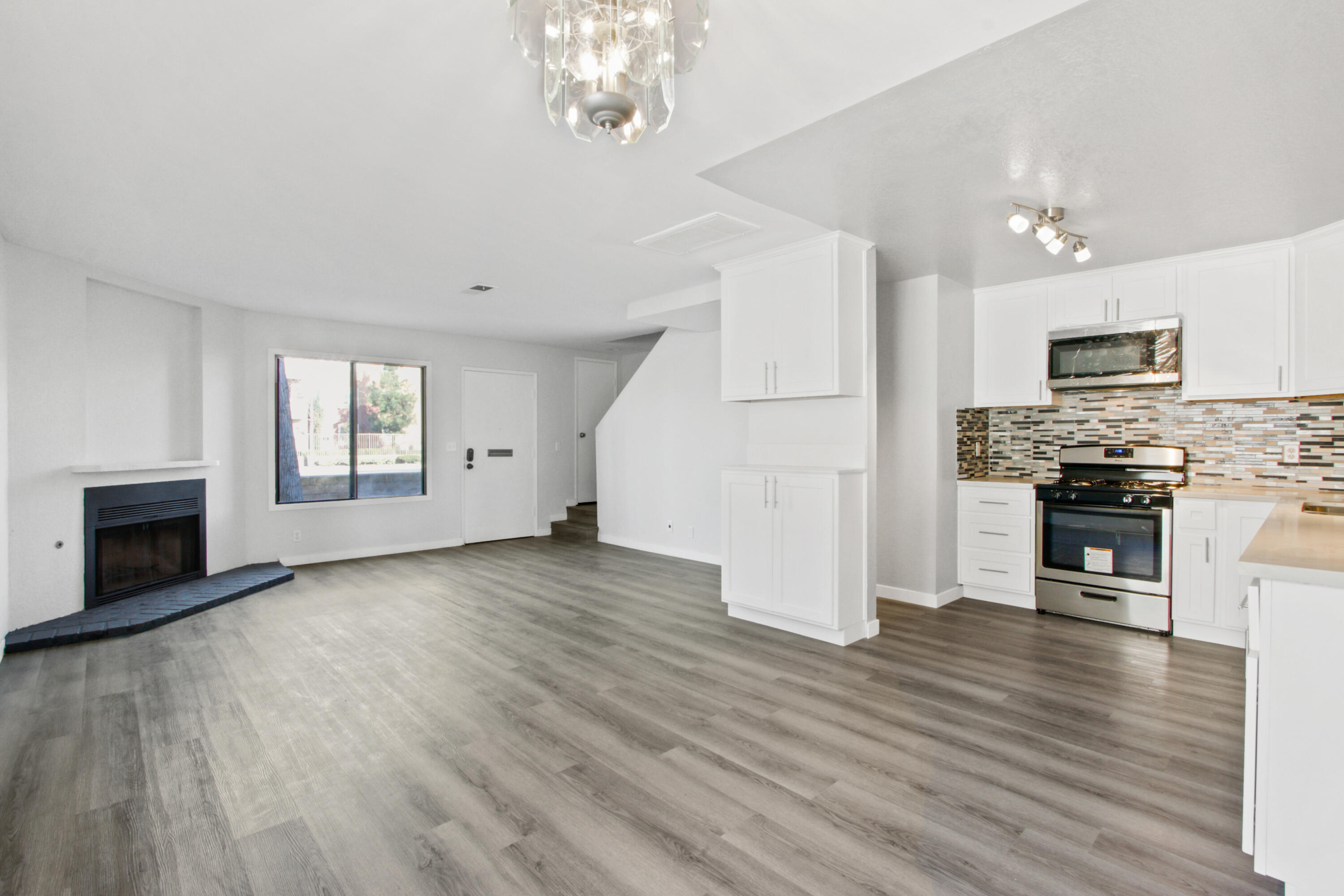 a view of empty room with kitchen and fireplace