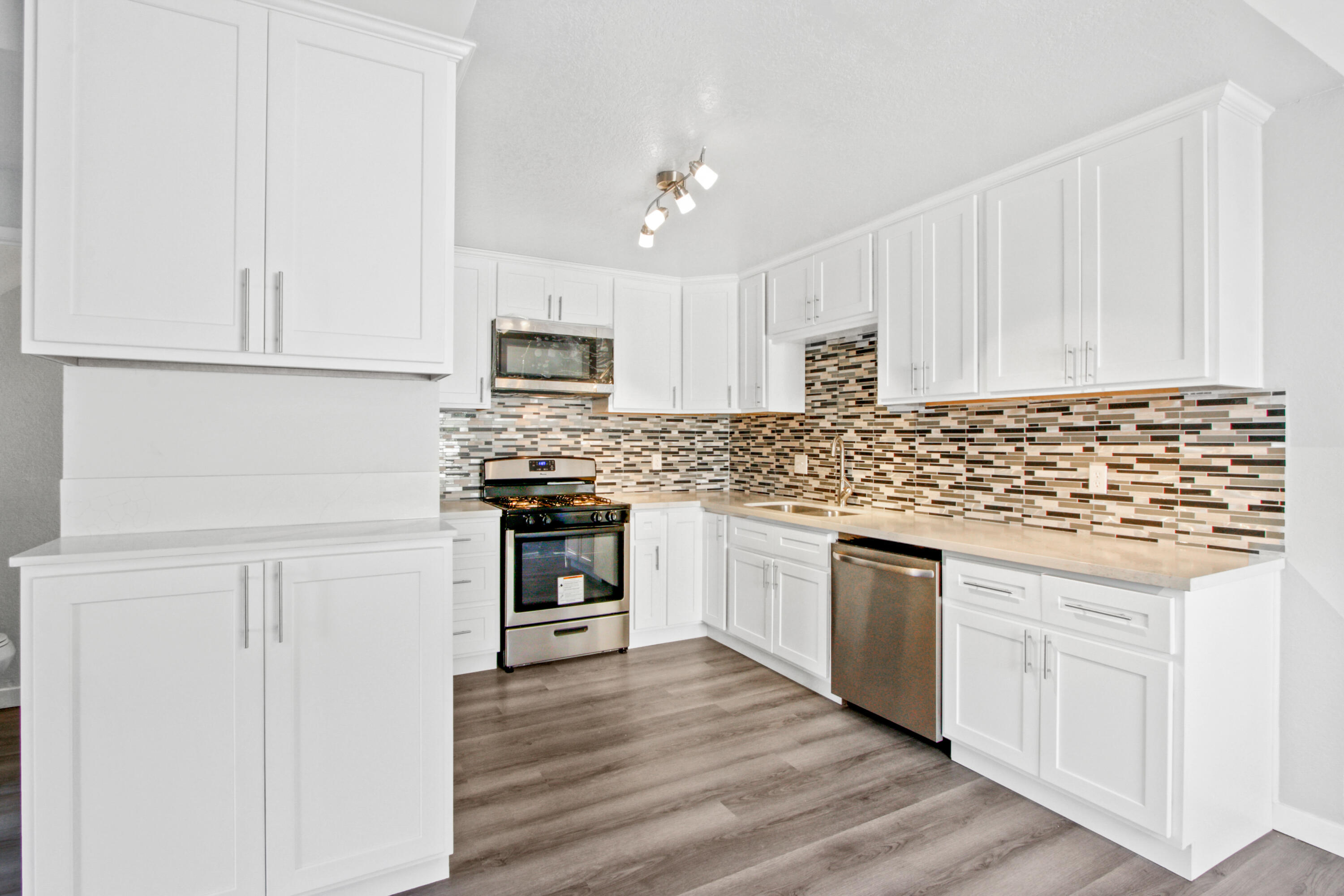 9542 Ball Road, Unit 1 Anaheim, CA 92804 - Photo 3 of 24 a kitchen with granite countertop white cabinets sink and stainless steel appliances