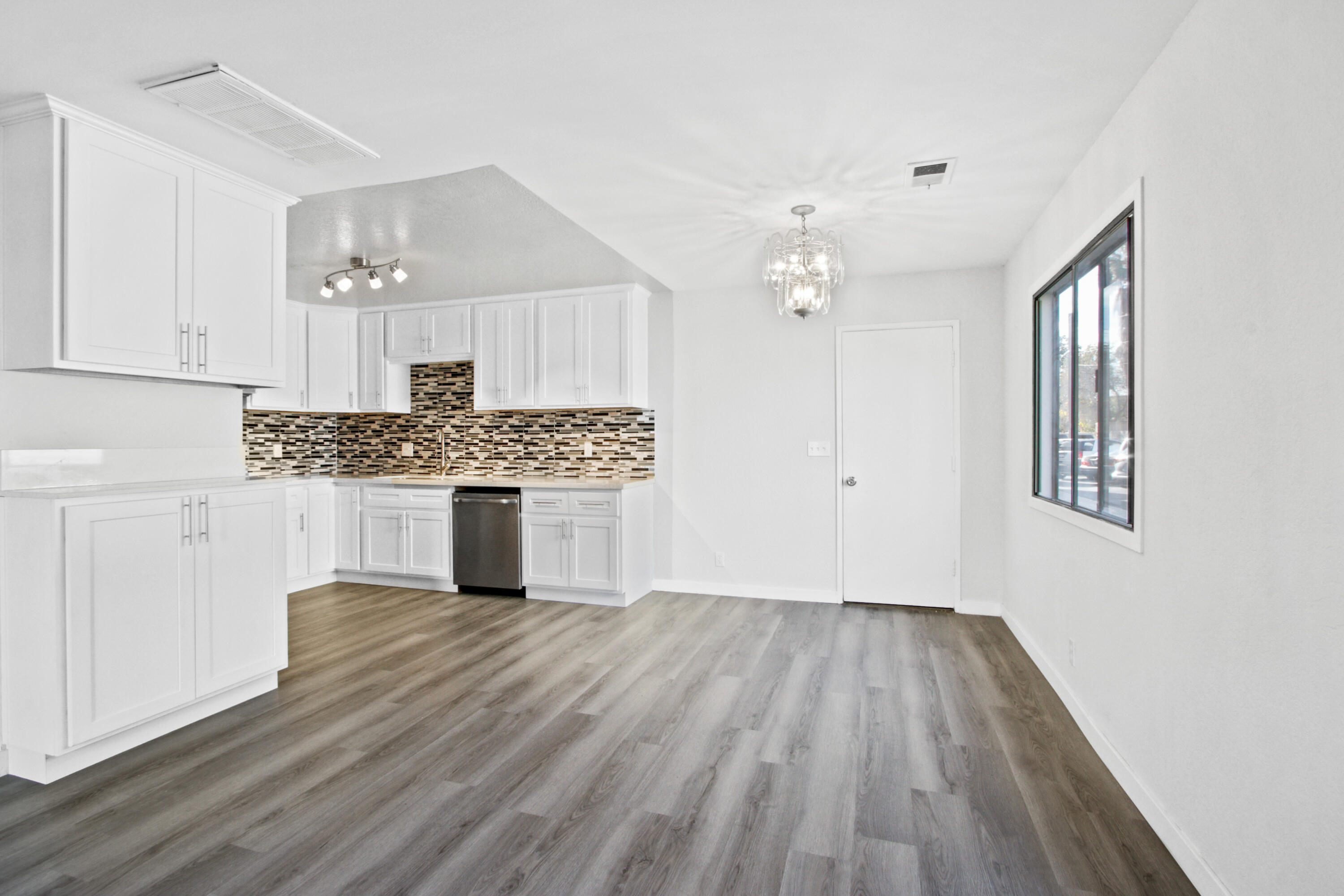9542 Ball Road, Unit 1 Anaheim, CA 92804 - Photo 5 of 24 a kitchen with granite countertop a stove a sink and white cabinets with wooden floor