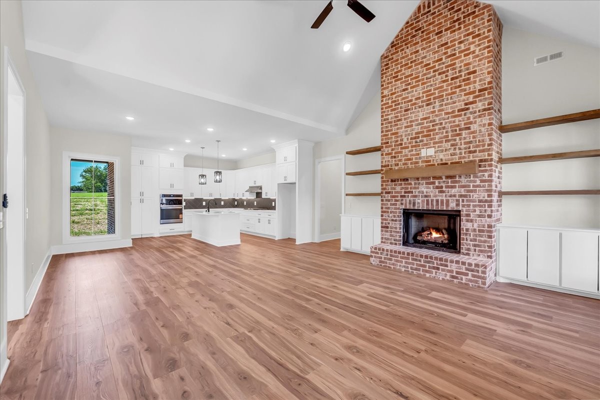 309 Hickory Grove Drive Morrison, TN 37357 - Photo 10 of 50 an empty room with wooden floor a fireplace and windows