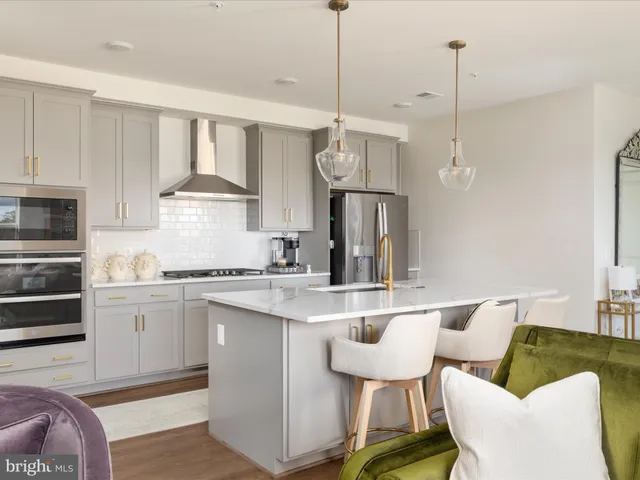 a kitchen with stainless steel appliances granite countertop a sink a stove a refrigerator and island with wooden floor