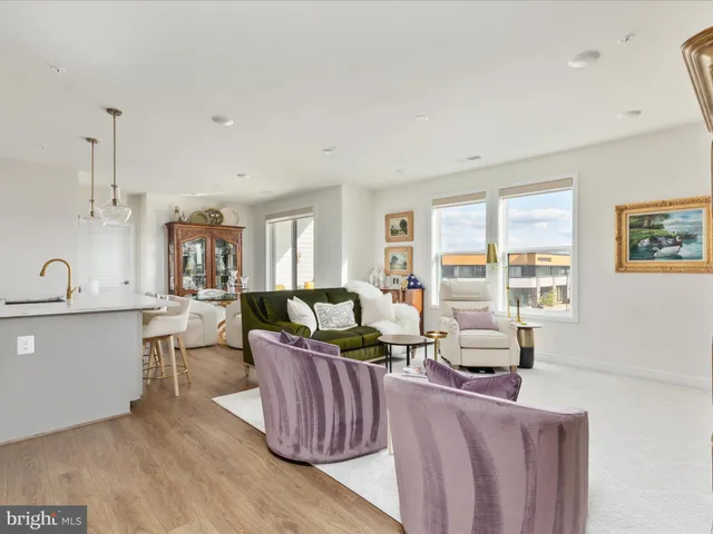 a living room with furniture a large window and wooden floor