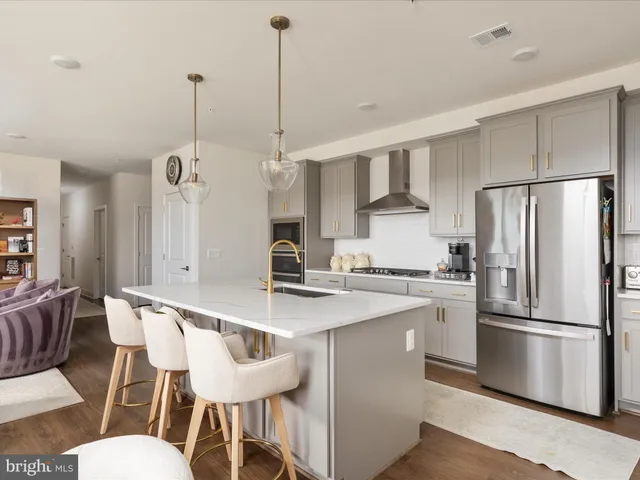 a kitchen with stainless steel appliances granite countertop a sink a stove a refrigerator and island with wooden floor