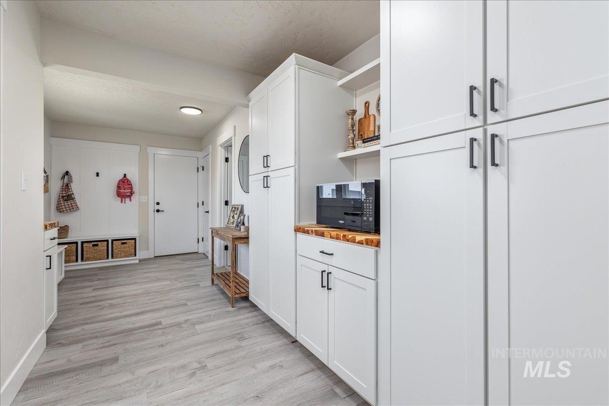 23011 Allendale Road Parma, ID 83660 - Photo 26 of 50 White shaker-style cabinetry with matte black hardware, wood-finish flooring, built-in storage bench, and recessed lighting