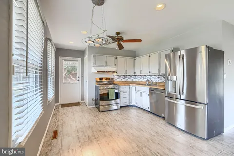 a kitchen with stainless steel appliances a stove a refrigerator and white cabinets with wooden floor