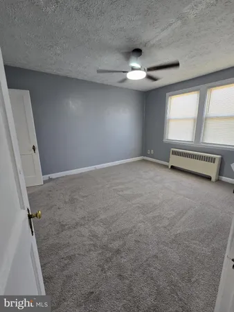 an empty room with windows and fan