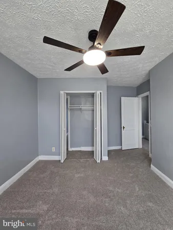 an empty room with closet and a ceiling fan