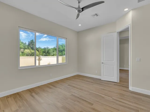 a view of empty room with wooden floor and fan