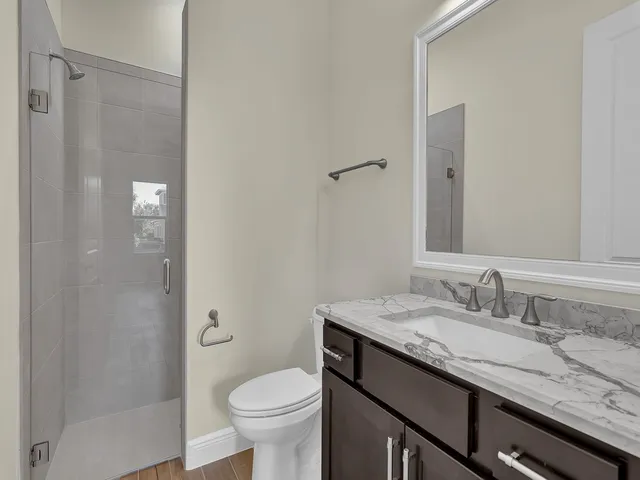 a bathroom with a granite countertop sink a toilet and shower