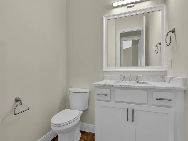 a bathroom with a toilet sink vanity and mirror