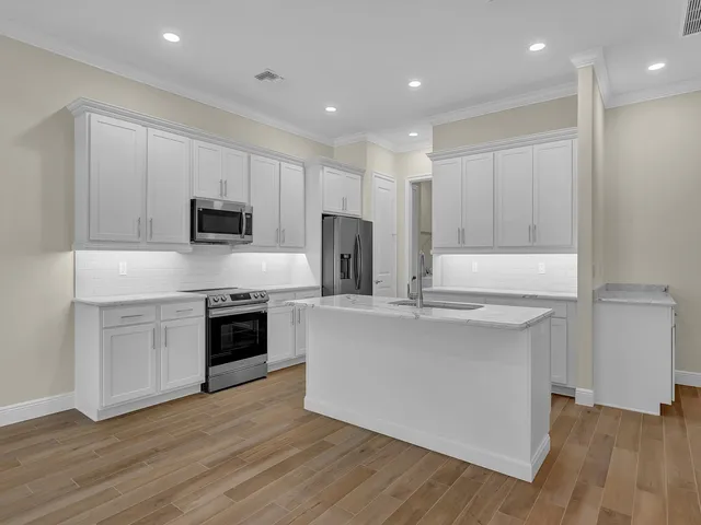 a kitchen with kitchen island granite countertop a sink cabinets and stainless steel appliances