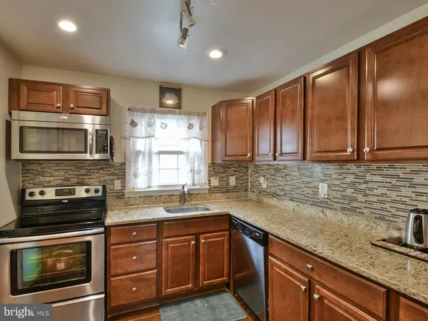 a kitchen with granite countertop stainless steel appliances a sink stove top oven and cabinets