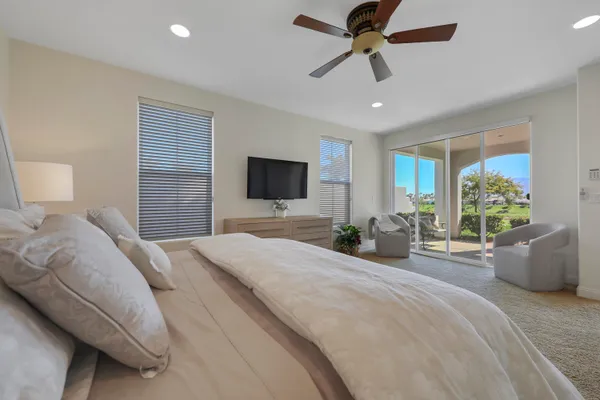 a bedroom with a bed a flat screen tv and a large window