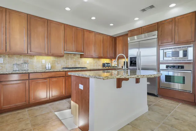a kitchen with stainless steel appliances granite countertop a stove a sink and a refrigerator