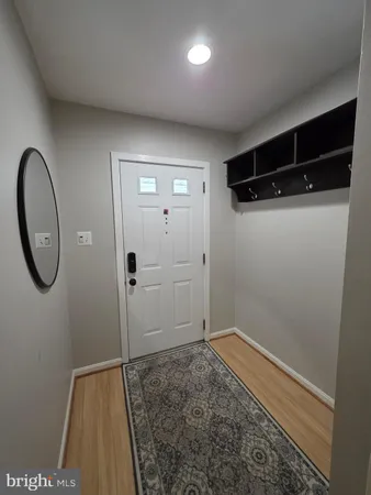 a view of an empty room with wooden floor and a fireplace