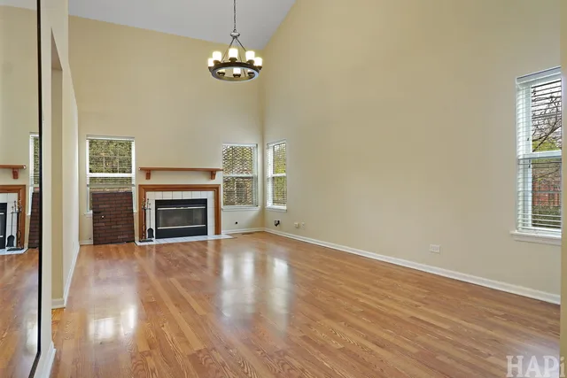 an empty room with wooden floor fireplace and windows