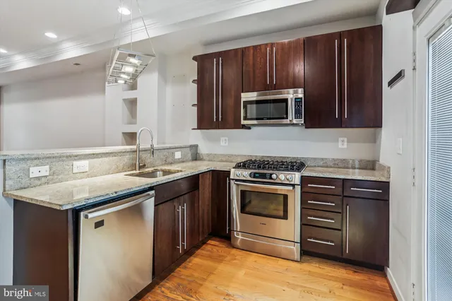 a kitchen with stainless steel appliances granite countertop wooden cabinets stove top oven and sink