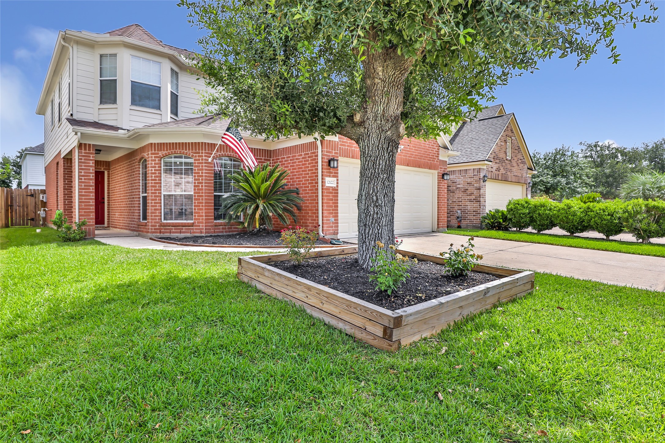 12122 Landsdown Ridge Way Humble, TX 77346 - Photo 2 of 34 This home features a well-maintained front yard with a mature tree in a raised planter. It has an inviting bay window, a red front door, and a neatly paved driveway leading to a two-car garage. Perfect for a family looking for a welcoming neighborhood setting.