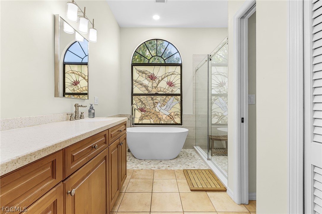 7747 Grande Pine Road Bokeelia, FL 33922 - Photo 23 of 45 a bathroom with a sink a mirror a window and a bathtub