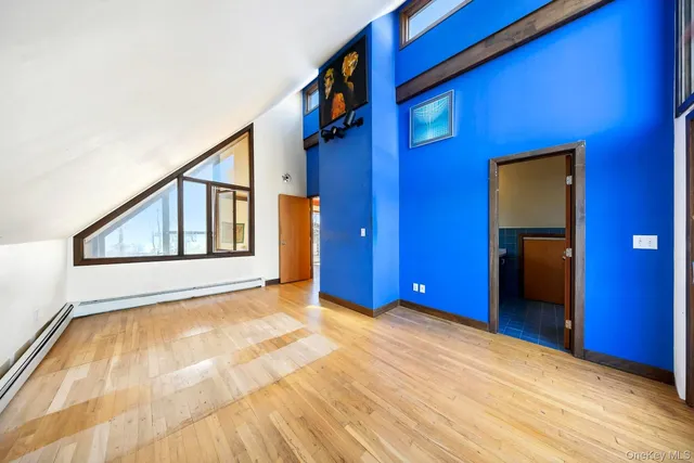 a view of an empty room with wooden floor and a bathroom