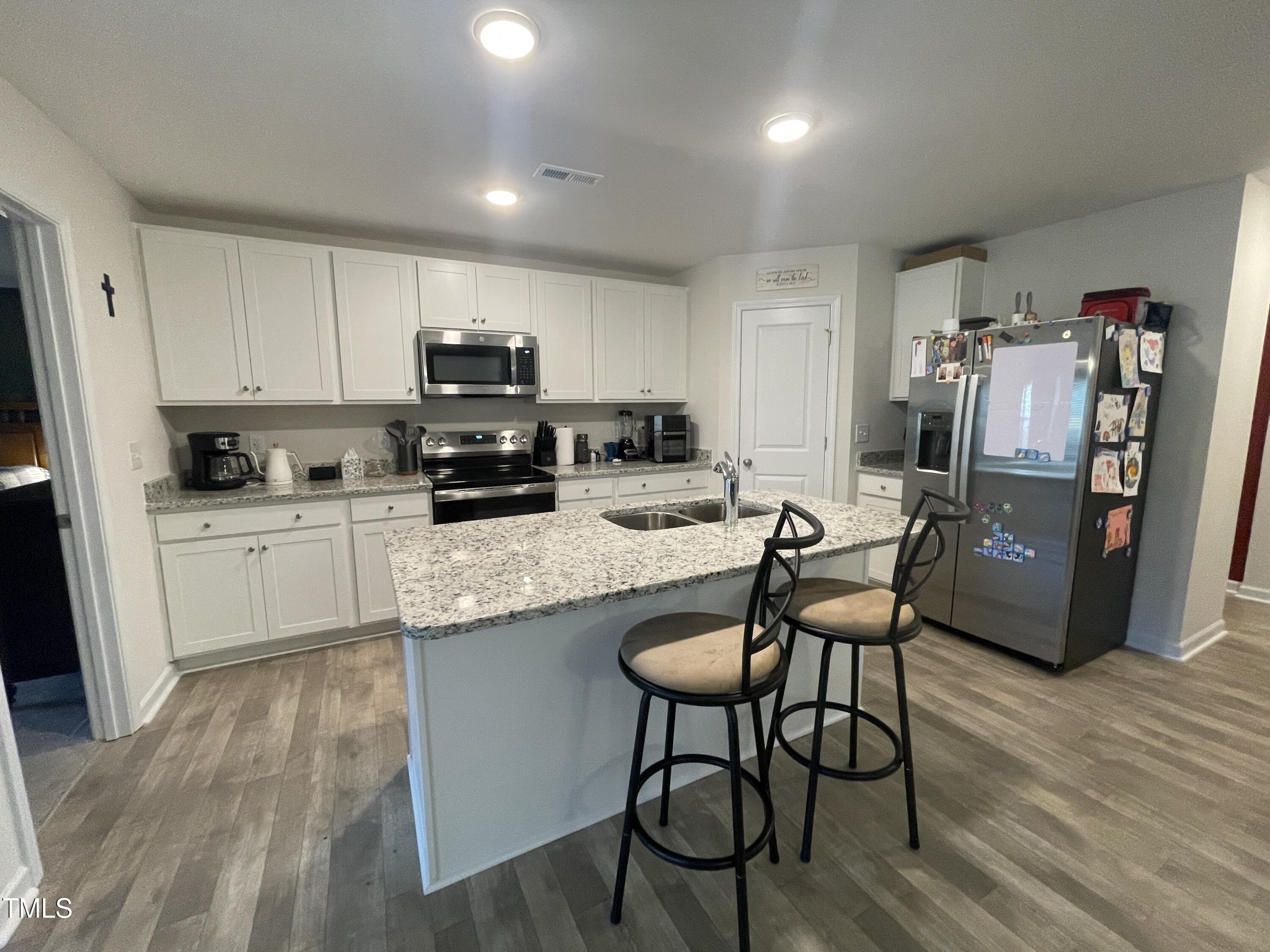 195 Presley Street Raeford, NC 28376 - Photo 10 of 37 a kitchen with stainless steel appliances granite countertop a stove top oven a refrigerator a sink and white cabinets with wooden floor