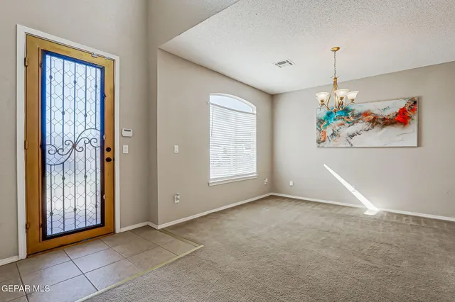 an empty room with chandelier fan and windows