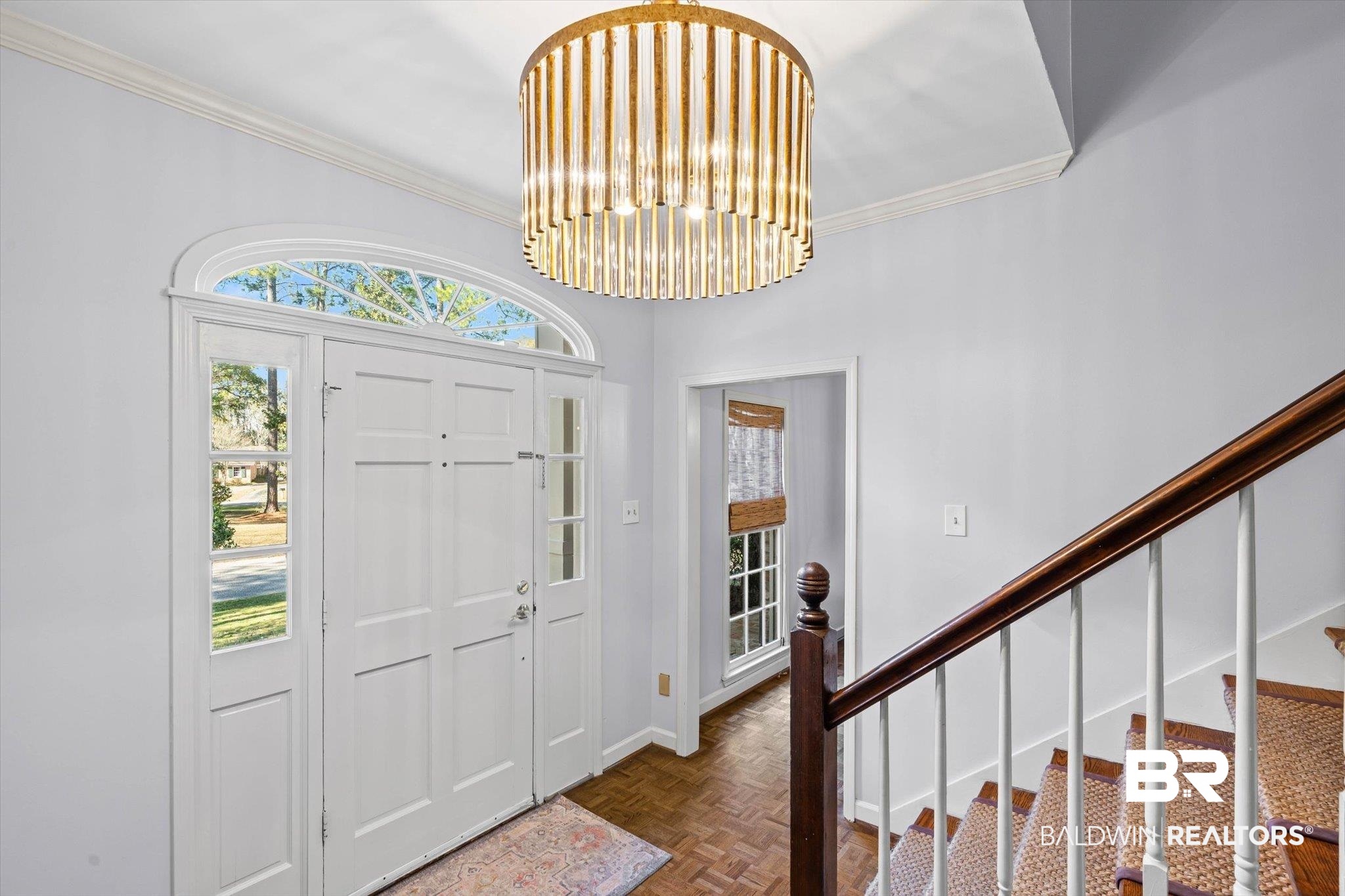 4776 Falls Church Road Mobile, AL 36608 - Photo 3 of 45 Entry foyer featuring double white paneled doors with sidelights, an arched transom window, a cylindrical chandelier with gold-toned accents, and parquet wood flooring