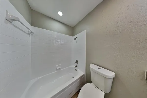 a white toilet sitting next to a bath tub