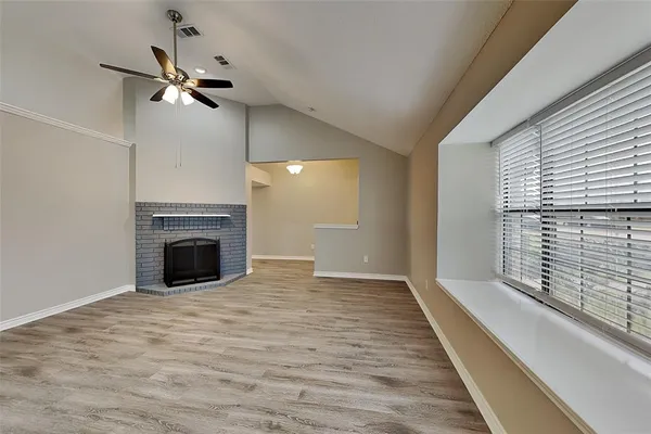 a view of an empty room with a fireplace and a window