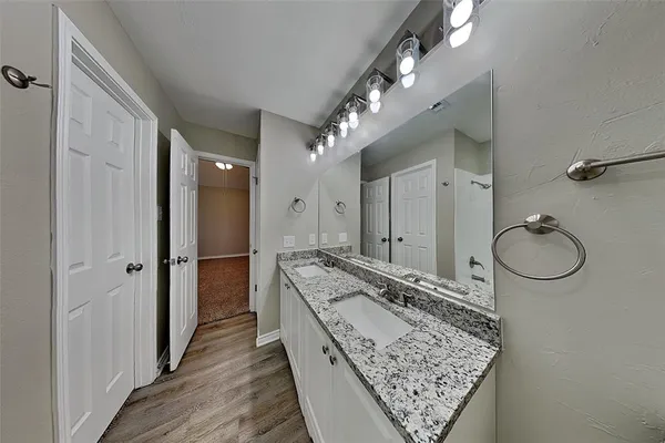 a bathroom with a granite countertop sink a mirror and shower