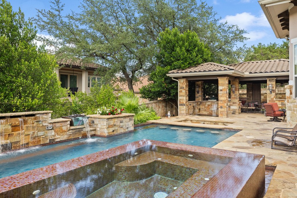 109 Largo Cove Austin, TX 78734 - Photo 39 of 40 An inviting backyard oasis awaits with a sparkling pool, integrated spa, and an adjacent outdoor kitchen under a covered patio.