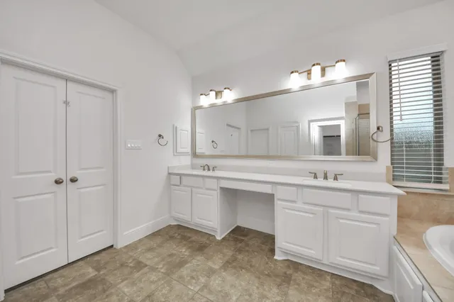 a large bathroom with a double vanity sink a large mirror and a bathtub