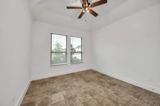 an empty room with a ceiling fan and carpet