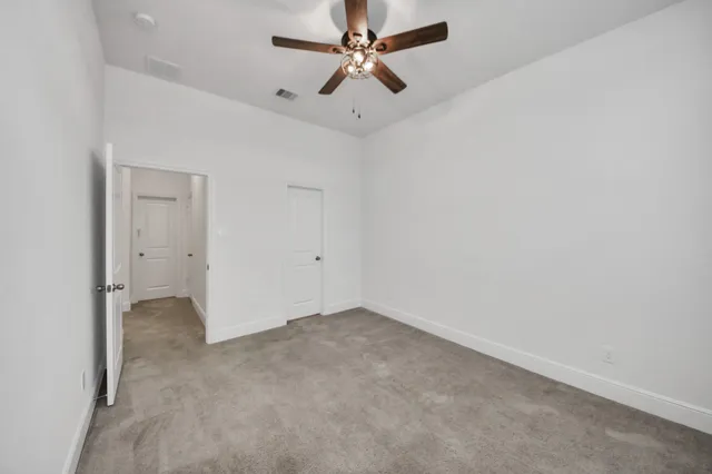 an empty room with windows and fan