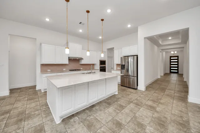 a large white kitchen with a refrigerator a stove top oven and kitchen island