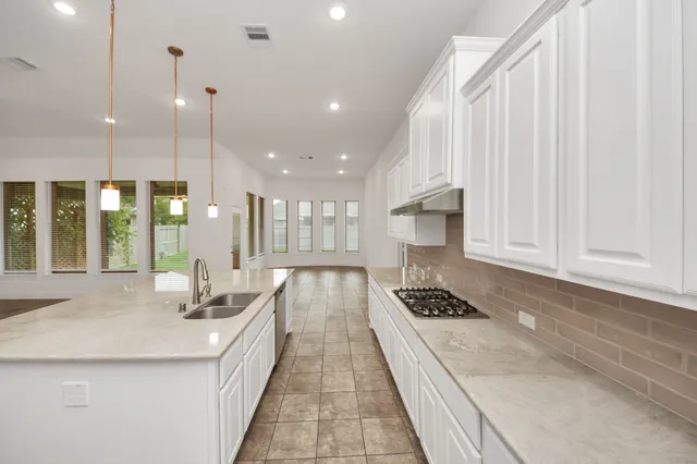 a kitchen with stainless steel appliances granite countertop a stove a sink and white cabinets with wooden floor