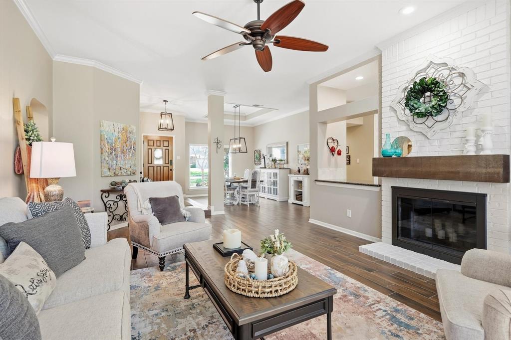 524 Post Oak Road Grapevine, TX 76051 - Photo 10 of 37 Wood-finish flooring, white brick fireplace with a wood mantel, crown molding, a ceiling fan with light, and a wooden front door