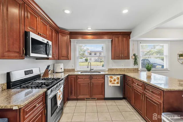 a large kitchen with stainless steel appliances granite countertop a stove top oven a sink dishwasher a dining table and chairs with wooden floor