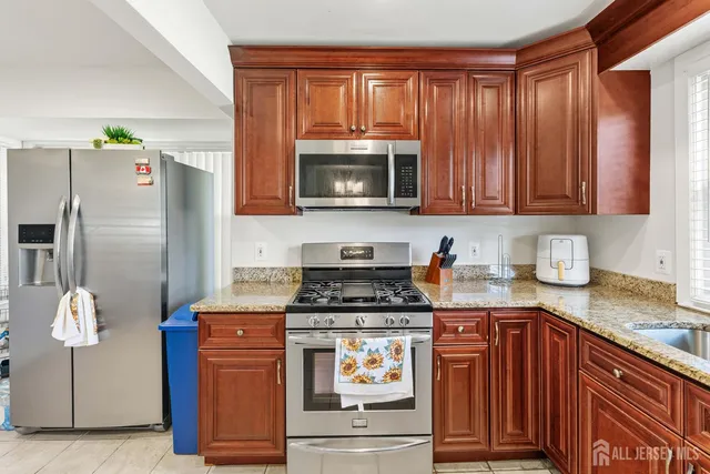 a kitchen with granite countertop a stove top oven microwave and refrigerator
