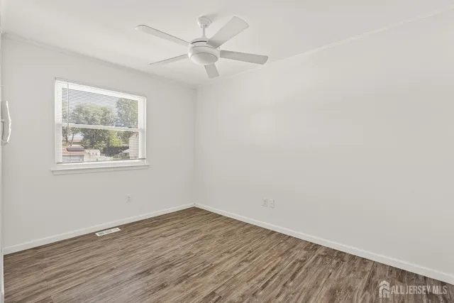 a view of an empty room with wooden floor and windows