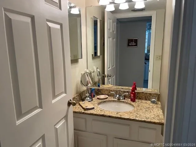 a bathroom with a granite countertop sink and a mirror