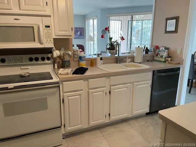 a kitchen with white cabinets and sink